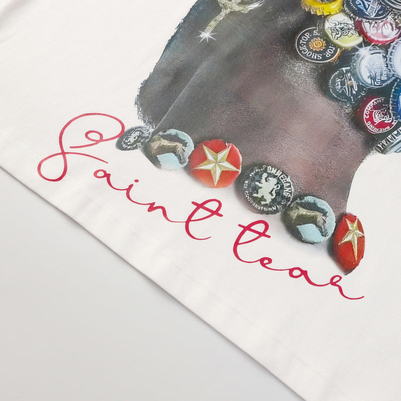 White graphic tee featuring a saint portrait made from colorful bottle caps and red script lettering