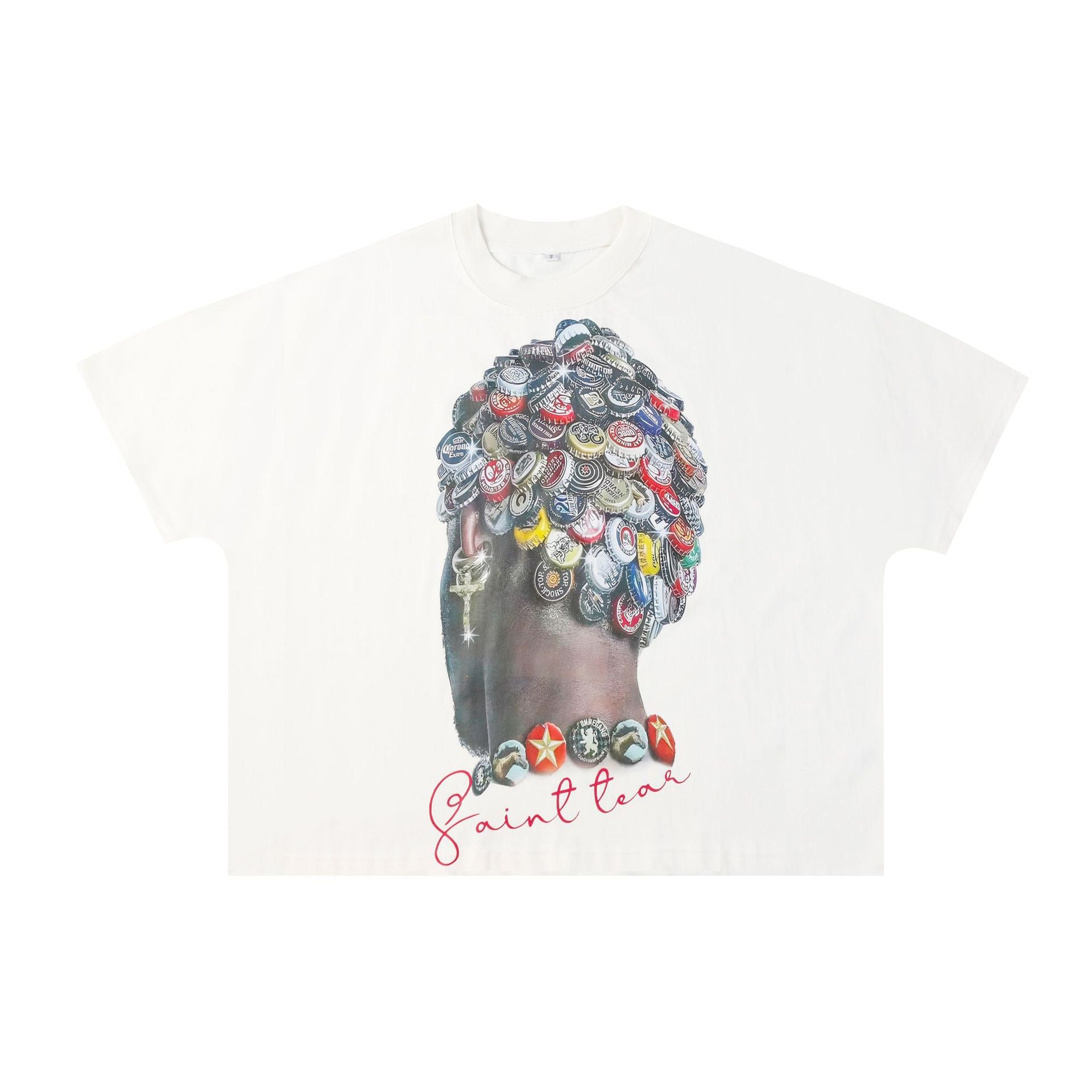 White oversized graphic tee with a bottle cap collage portrait illustration and handwritten Saint script on the front