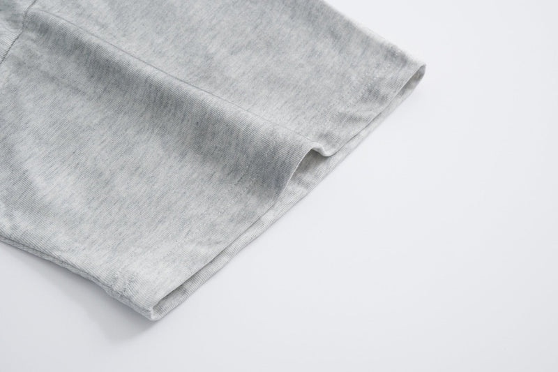 Close-up of light gray cotton streetwear tee sleeve with soft textured fabric and folded hem on white background