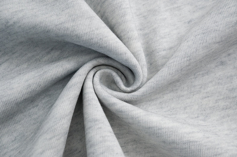 Close-up of light gray cotton T-shirt fabric with a twisted swirl texture and soft streetwear tee material
