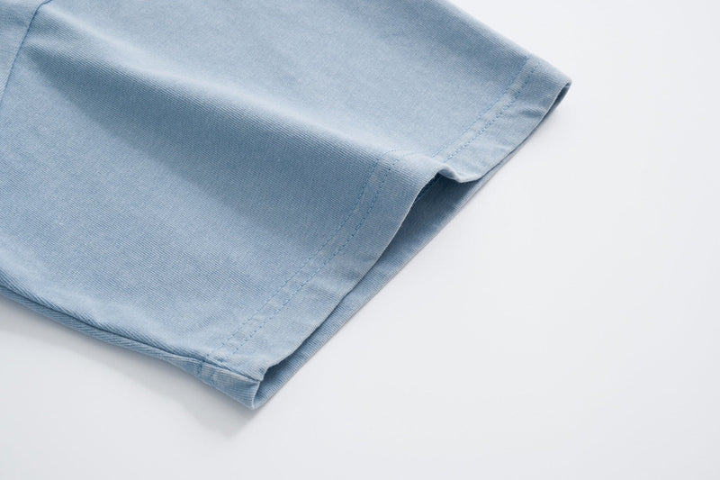Light blue cotton T-shirt sleeve hem with double stitching on a clean white background