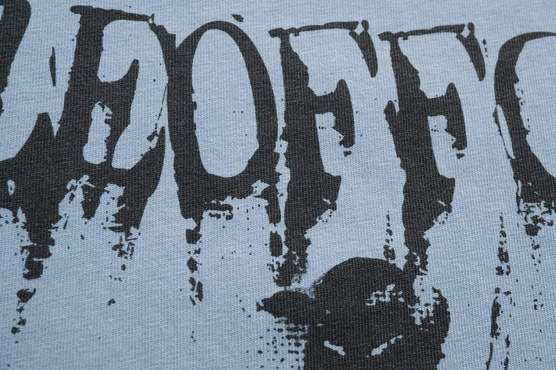 Close-up of a light gray graphic tee with distressed black gothic lettering and a shadowy ghost face print