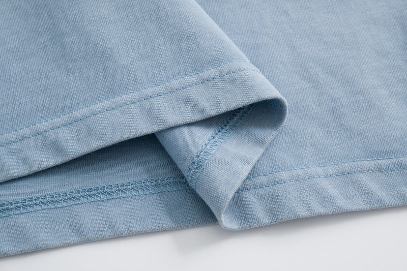 Light blue cotton T-shirt hem with visible stitching and folded sleeve detail on a clean white background
