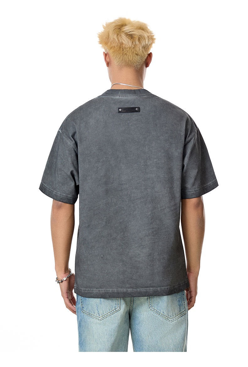Back view of a vintage washed dark gray heavyweight tee with rivet detail, worn with light blue jeans