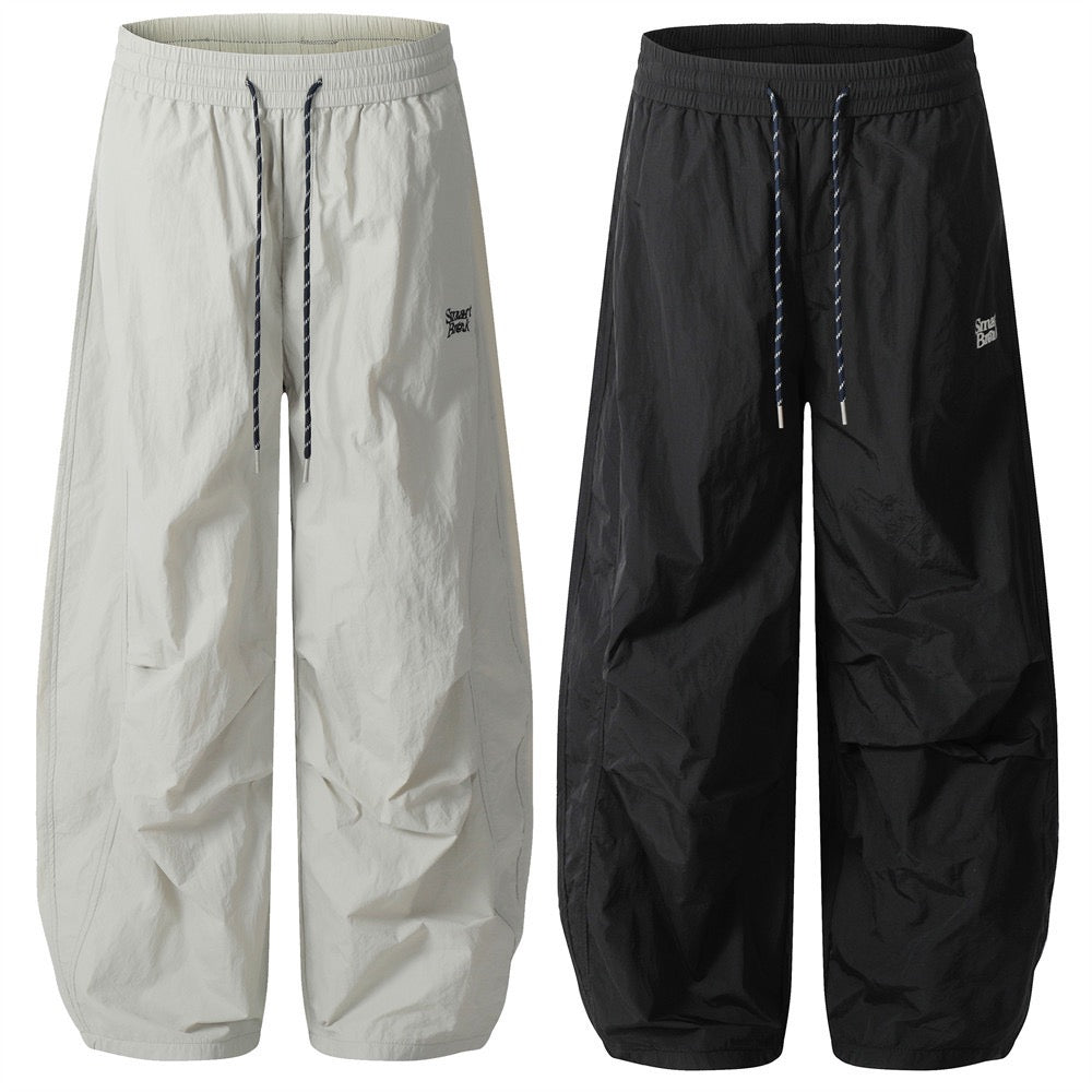 Smart Break wide-leg crinkle nylon track pants in cream and black with twisted drawstring, front view