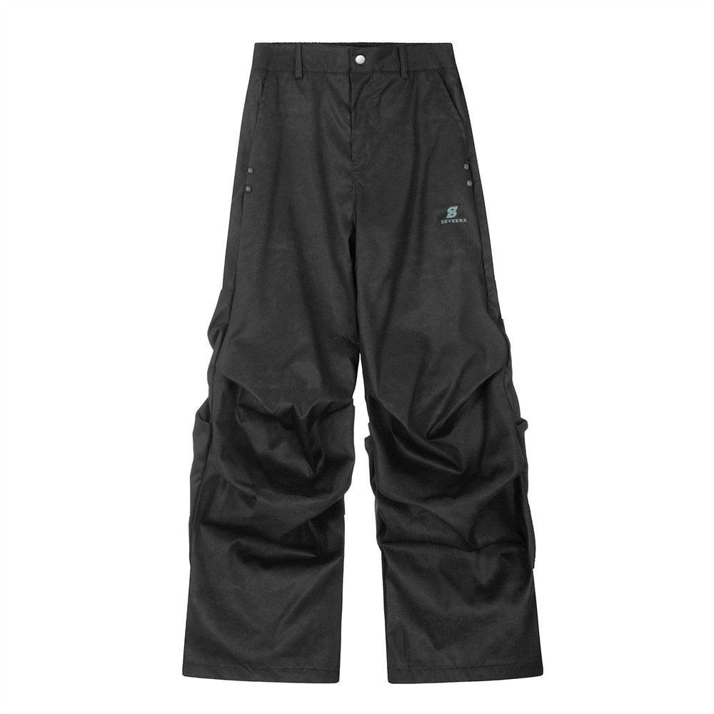 Front view of black wide-leg sculpted panel cargo pants with layered 3D knee panels and snap-button side detailing
