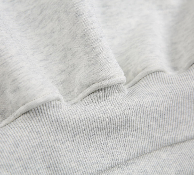 Close-up of light gray ribbed hem and gathered sweatshirt fabric