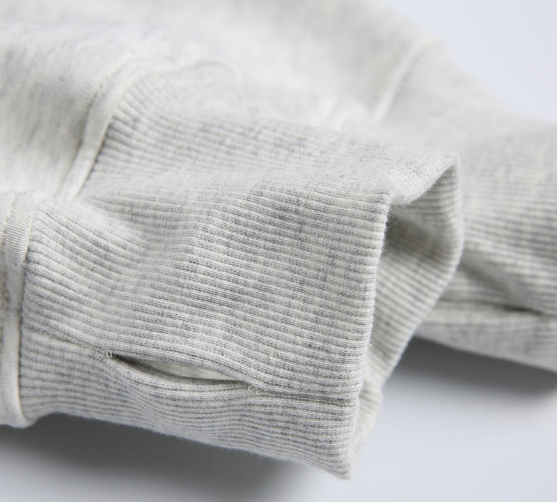 Close-up of light gray ribbed cuff with thumb hole opening