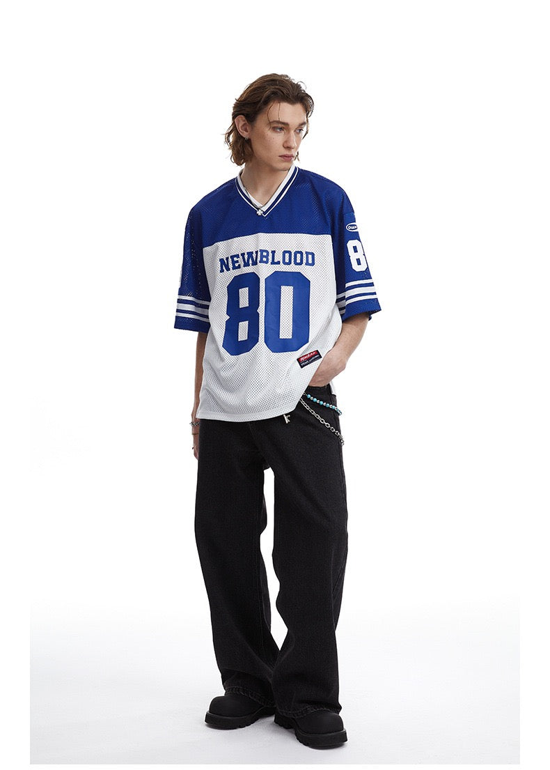 Model wearing a blue and white Newblood 80 football jersey tee with black wide-leg pants on a white background