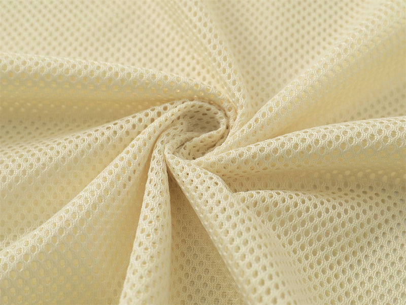 Close-up of cream mesh fabric with a soft perforated texture, shown in a gathered swirl for a streetwear tee