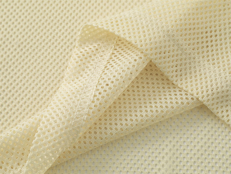 Cream mesh fabric close-up with breathable perforated texture, showing the lightweight material of a Y2K streetwear graphic tee