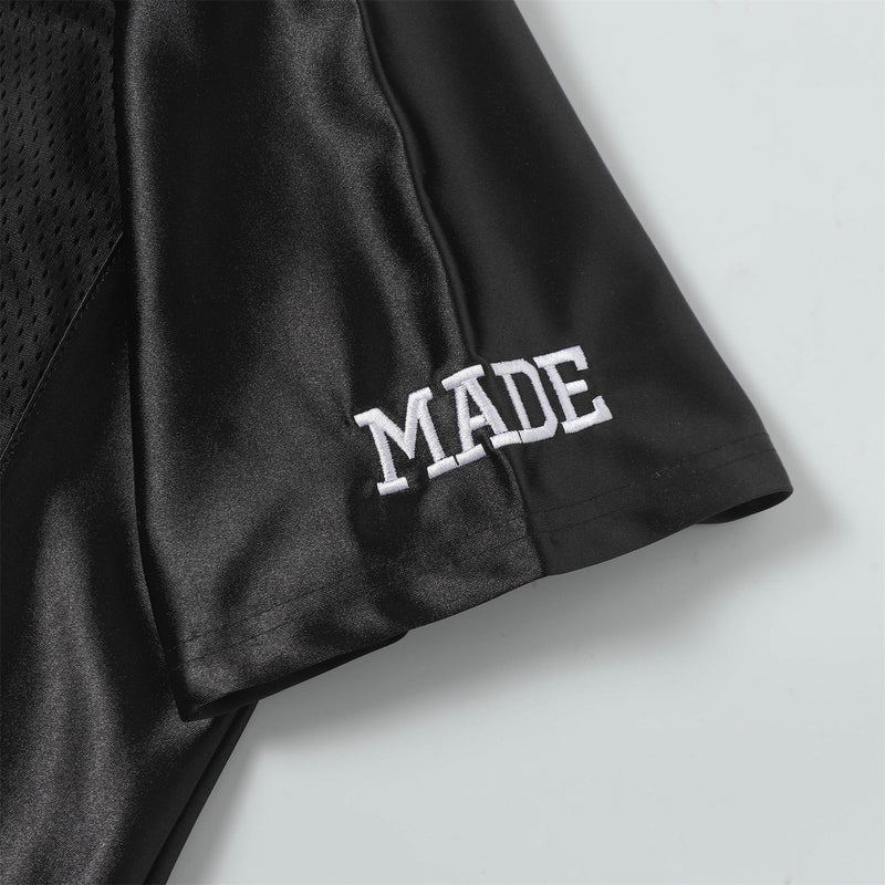 Black mesh football jersey tee with white MADE embroidery on the sleeve, close-up streetwear detail