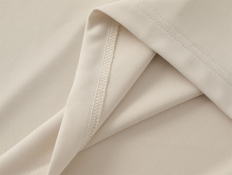 Close-up of beige cotton T-shirt fabric with folded seam and visible stitching detail