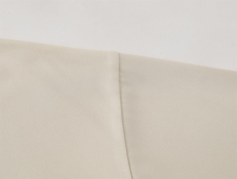 Close-up of cream cotton fabric with folded oversized T-shirt texture and clean minimalist finish