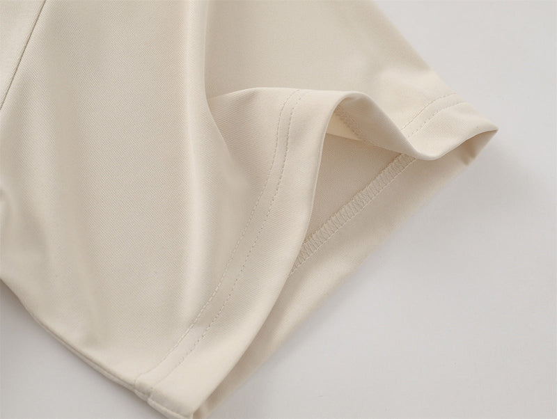 Close-up of an oversized cream cotton T-shirt sleeve with visible hem stitching and soft heavyweight fabric texture