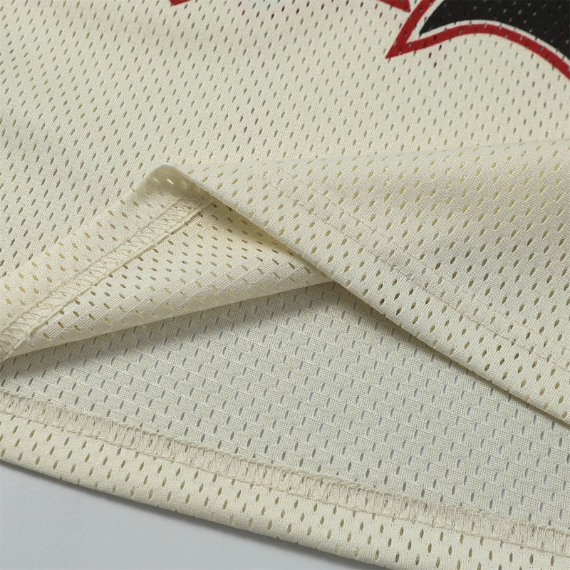 Cream mesh football jersey fabric with stitched hem and partial red-and-black graphic detail