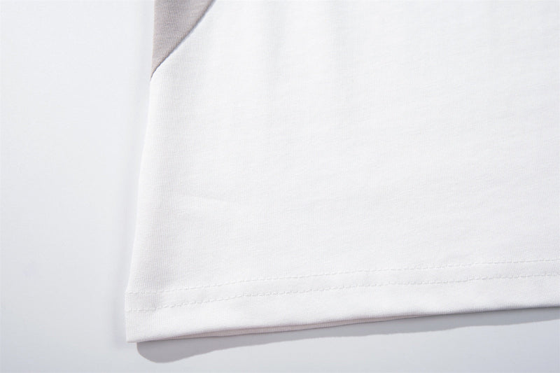 Close-up of a white raglan streetwear tee with gray shoulder panel and stitched hem detail
