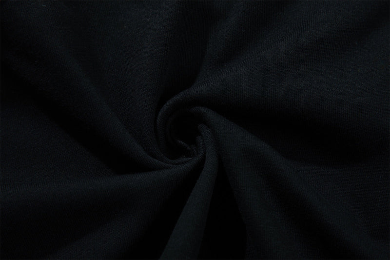 Black knit varsity graphic tee fabric with a textured close-up and soft folded swirl detail