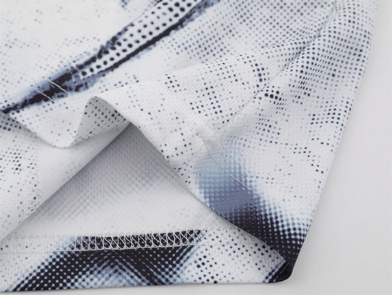 Close-up of gray distressed mesh jersey fabric with black speckled print and stitched hem detail