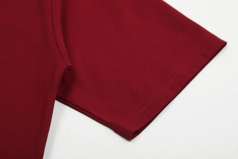 Close-up of a burgundy streetwear tee sleeve with clean hem stitching on a white background
