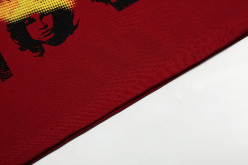 Close-up of a red streetwear tee with black portrait graphic and visible hem stitching on the fabric