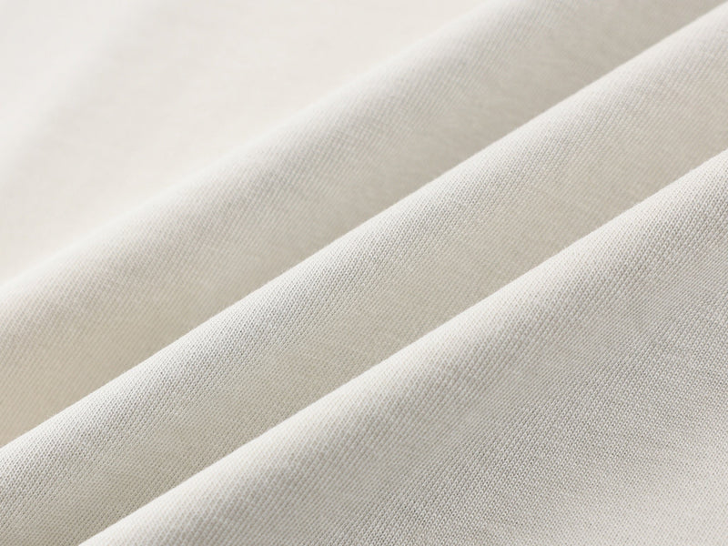Close-up of soft cream knit fabric on a color-block sporty street tee with subtle textured folds