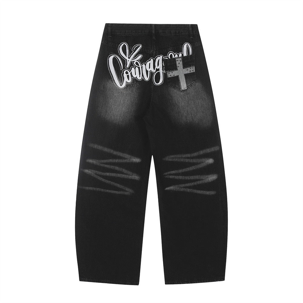 Back view of black washed denim pants with Courage embroidered script and cross pocket detail