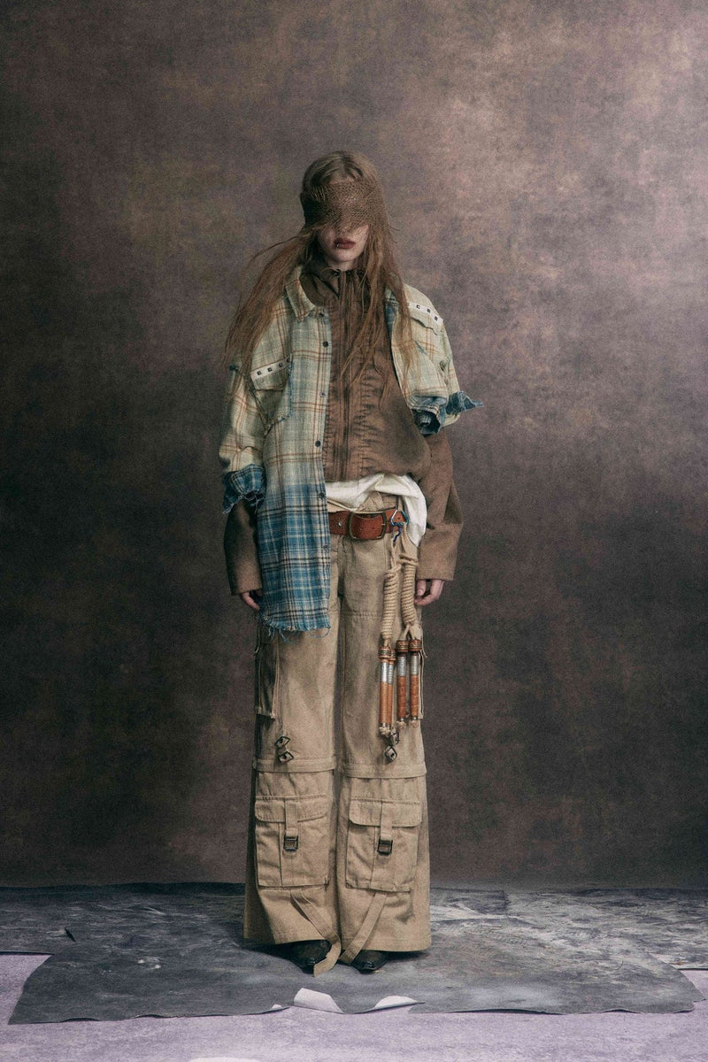 Model wearing a blue and cream plaid flannel shirt over layered brown and beige clothing