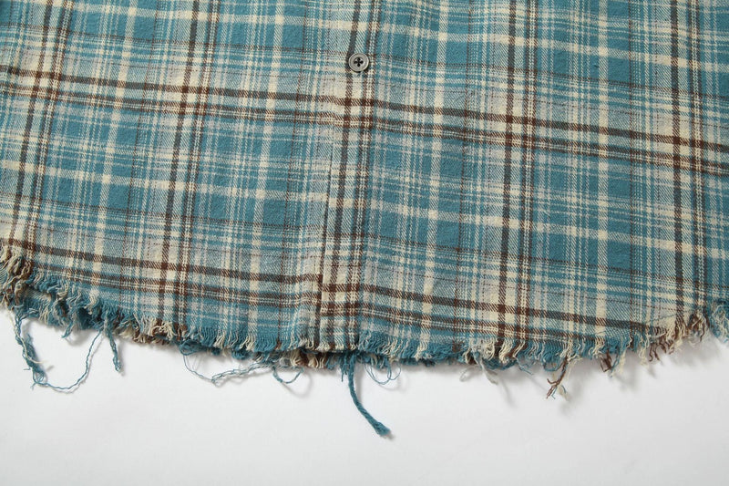 Close-up of the blue plaid shirt hem with frayed raw edge and button placket