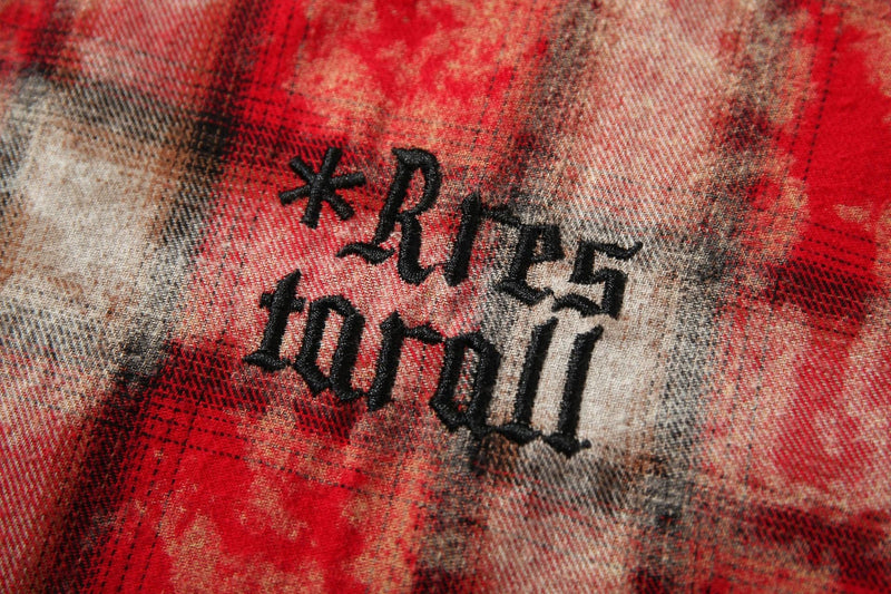 Close-up of black embroidered lettering on red plaid fabric