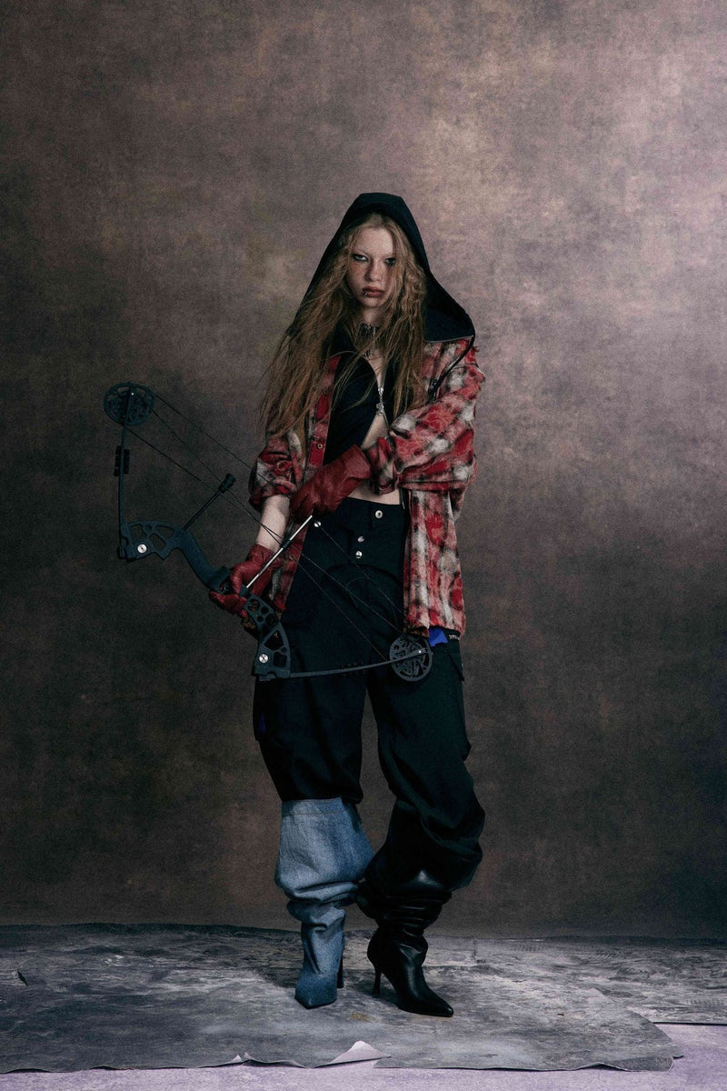 Model holding a bow while wearing red distressed plaid patchwork shirt