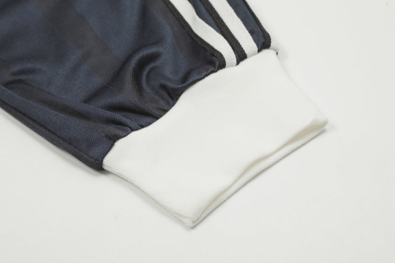 Close-up of black jersey sleeve cuff with white ribbed hem and triple stripe
