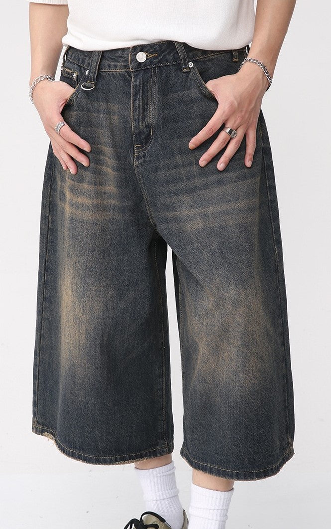 Close front view of dark washed wide-leg denim shorts with faded thigh details
