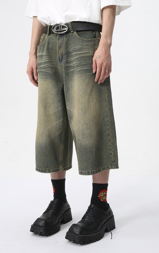 Baggy fit wide-leg denim shorts with faded green wash, angled front view on model