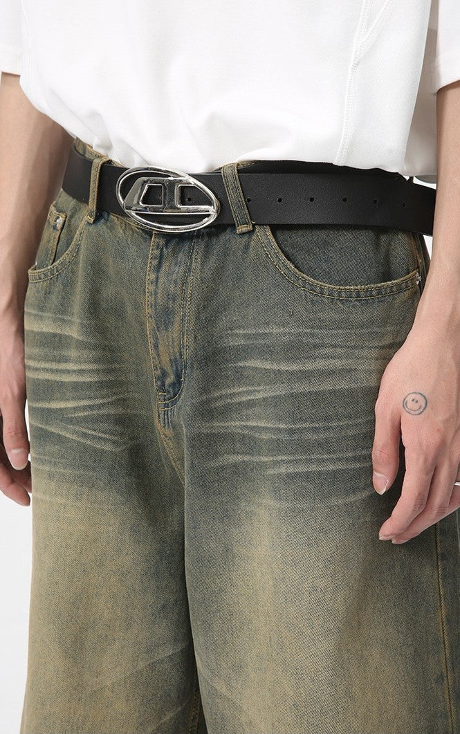 Close-up front waist of faded green denim shorts with black belt and silver oval buckle