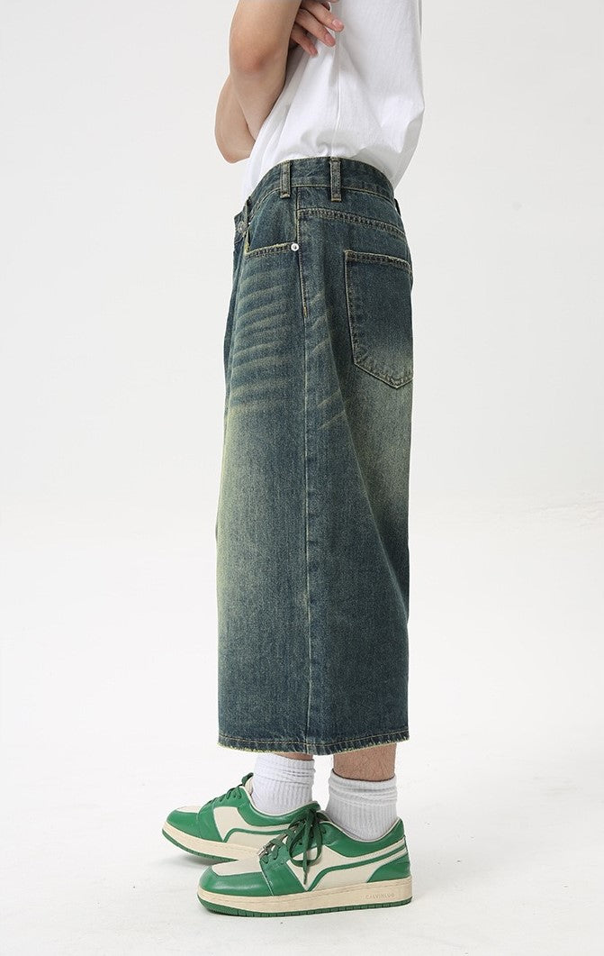 Wide leg vintage wash denim shorts in dark blue, side view on a model