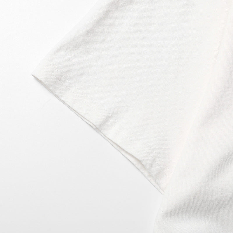 Close-up of a white oversized streetwear tee sleeve with clean hem and soft ribbed cotton texture