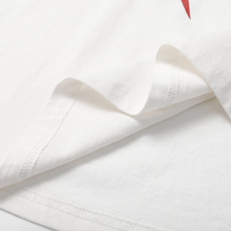 Close-up of a white oversized graphic tee with visible hem stitching and a red spider print detail