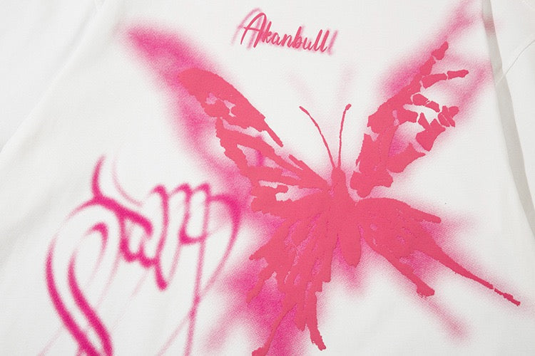 White oversized graphic tee with pink butterfly graffiti print and script lettering on the front