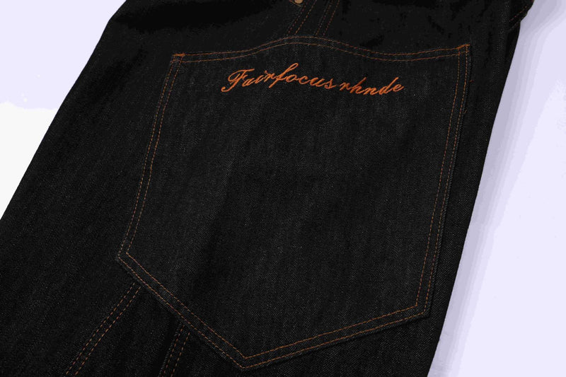 Close-up of back pocket on dark indigo denim jorts with orange script embroidery