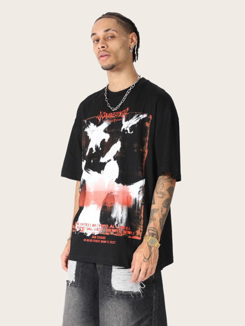 Oversized black tee with distressed raven graphic and red accents, styled on a model with streetwear jeans and chain necklace