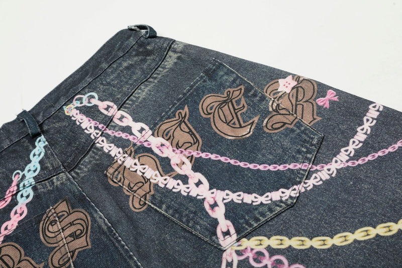 Close-up of back pocket on dark denim shorts with brown graffiti letters and pastel chains