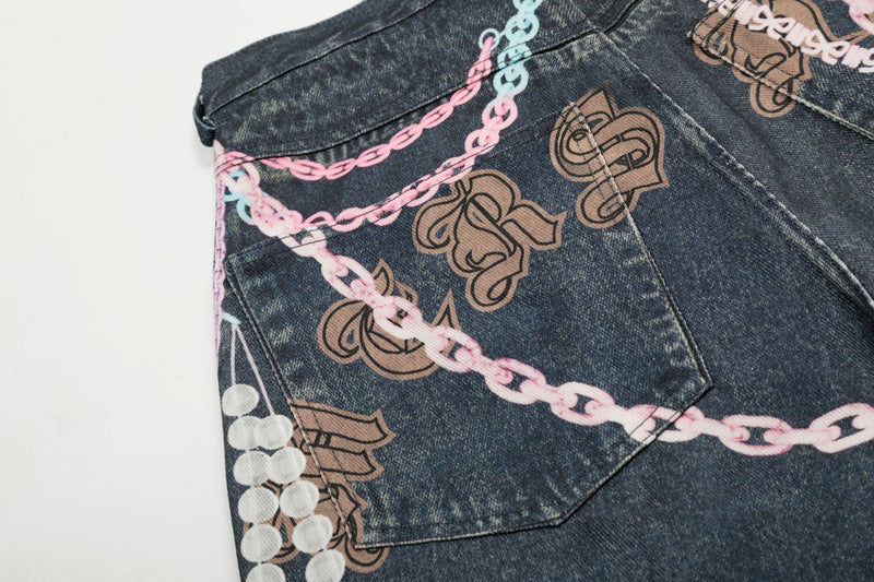 Close-up of back pocket area on dark denim shorts with pink chains and brown graffiti letters