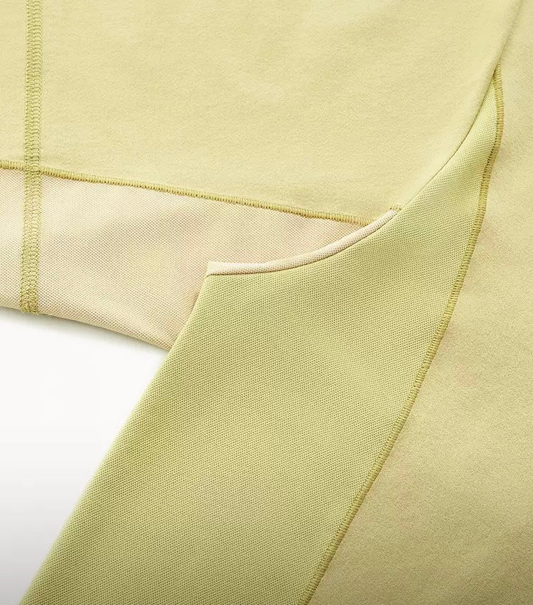 Close-up of a pale yellow color-block cotton T-shirt with textured panel stitching and curved seam details