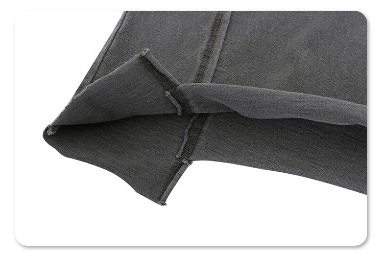Dark gray vintage washed cotton tee with visible split hem and raw-edged side seam detail close-up