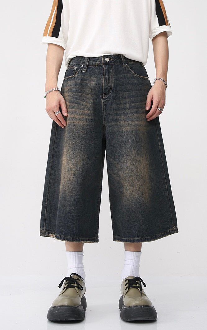 Model wearing dark washed wide-leg denim shorts with cropped hem and loose fit