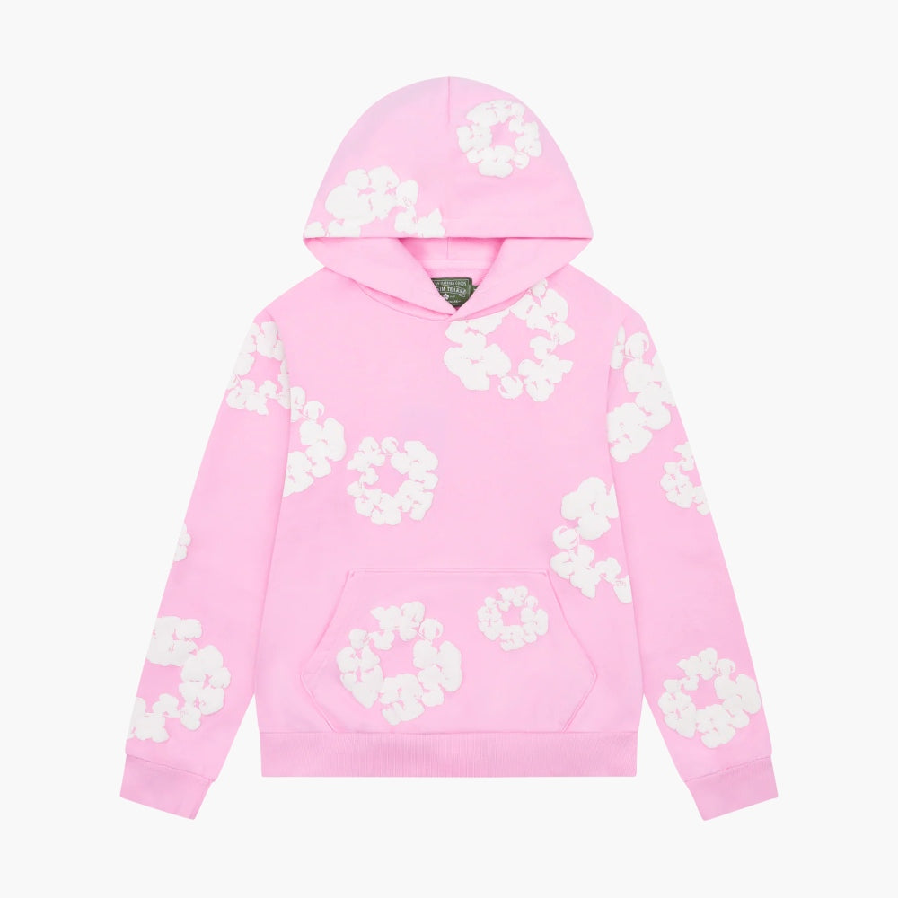 The Pink “Cotton Wreath” Denim Tears Hoodie is a light pink streetwear pullover featuring white floral prints across the front, sleeves, and hood, plus a front kangaroo pocket for comfort and style.