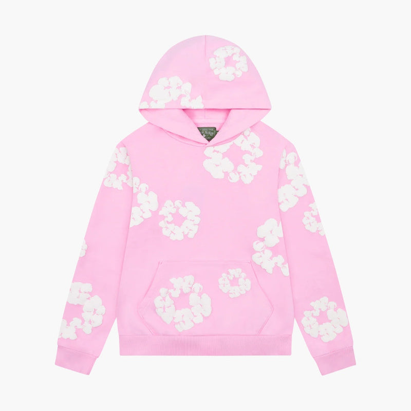 The Pink “Cotton Wreath” Denim Tears Hoodie is a light pink streetwear pullover featuring white floral prints across the front, sleeves, and hood, plus a front kangaroo pocket for comfort and style.