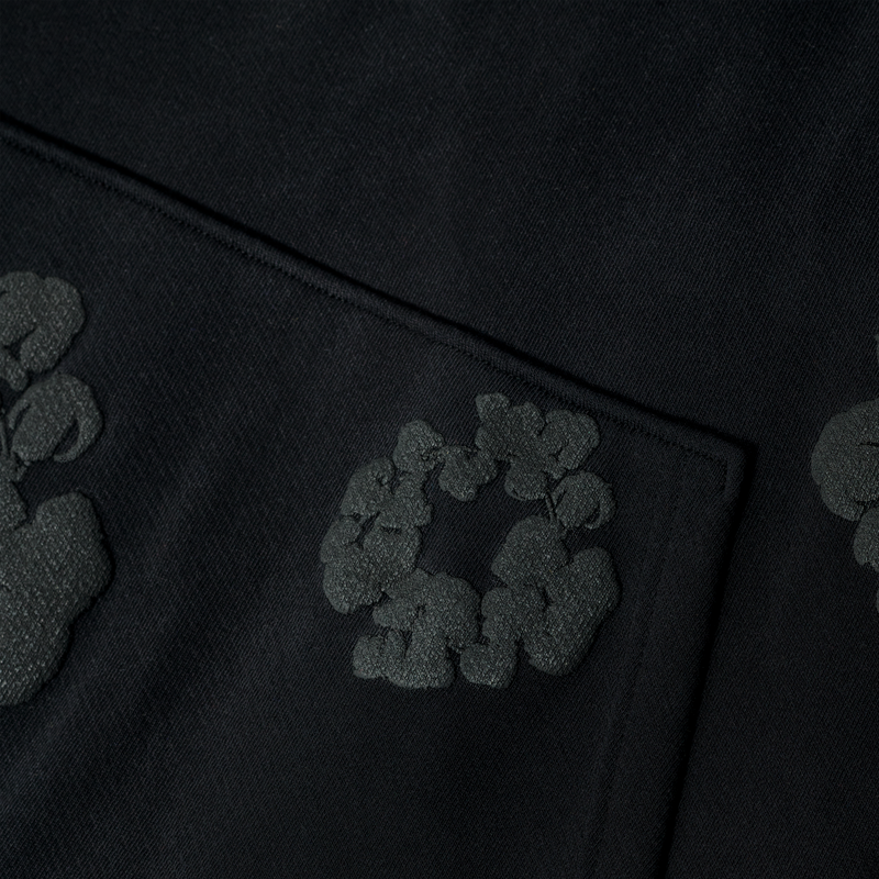 Close-up of the Black Monochrome “Cotton Wreath” Denim Tears Hoodie, a minimal streetwear sweatshirt with a subtle textured circular pattern and intricate weave, inspired by classic Denim Tears design.