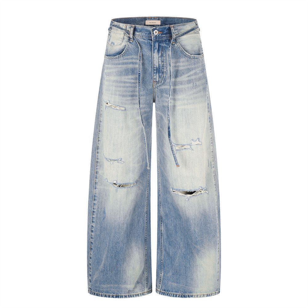 Men's wide-leg distressed jeans in gradient washed blue denim with ripped details and contrast back pocket patch